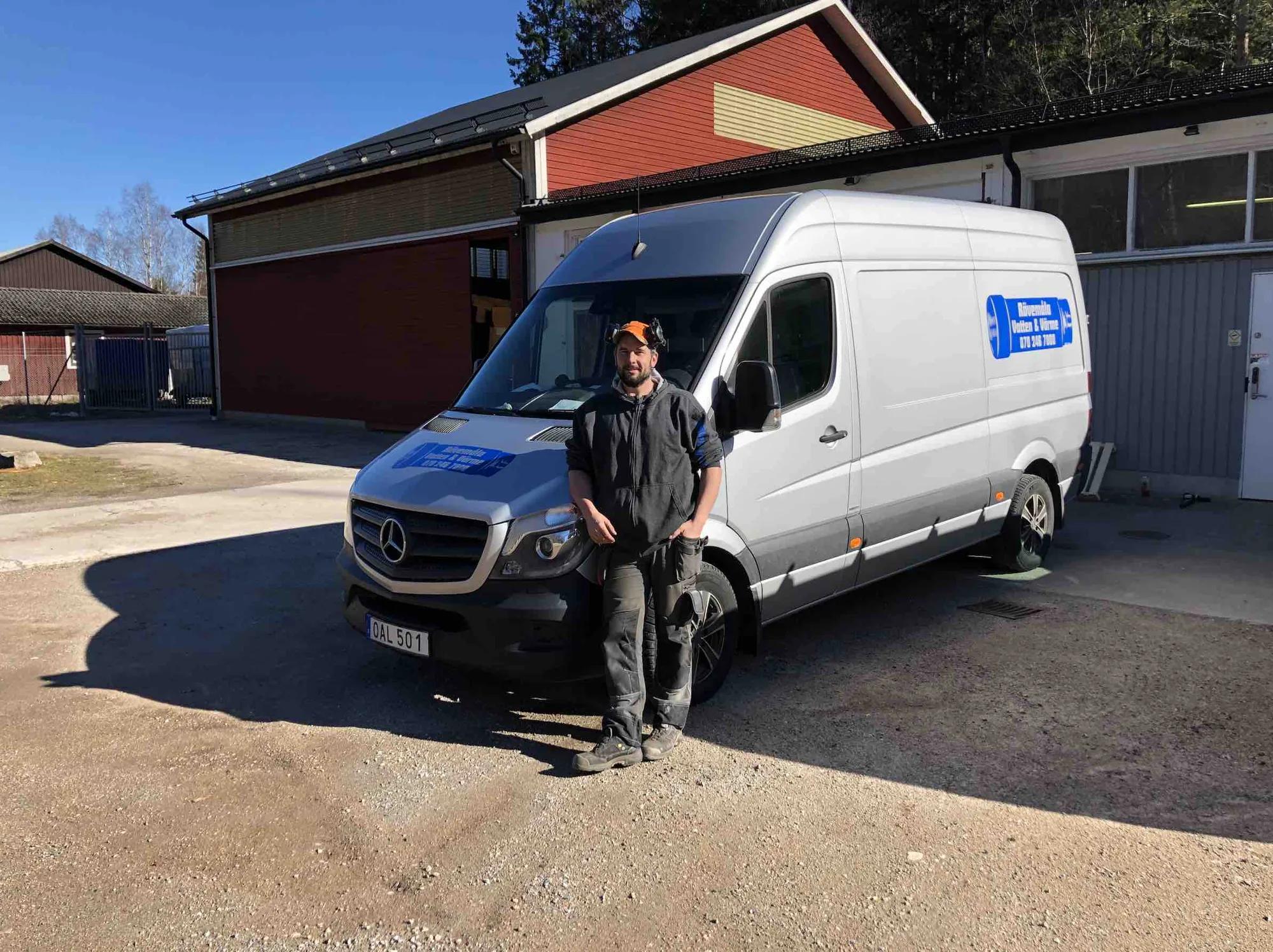 Tobias Hjelmberg, snickare, vid en av firmans vita bilar med det blå röret på sidan