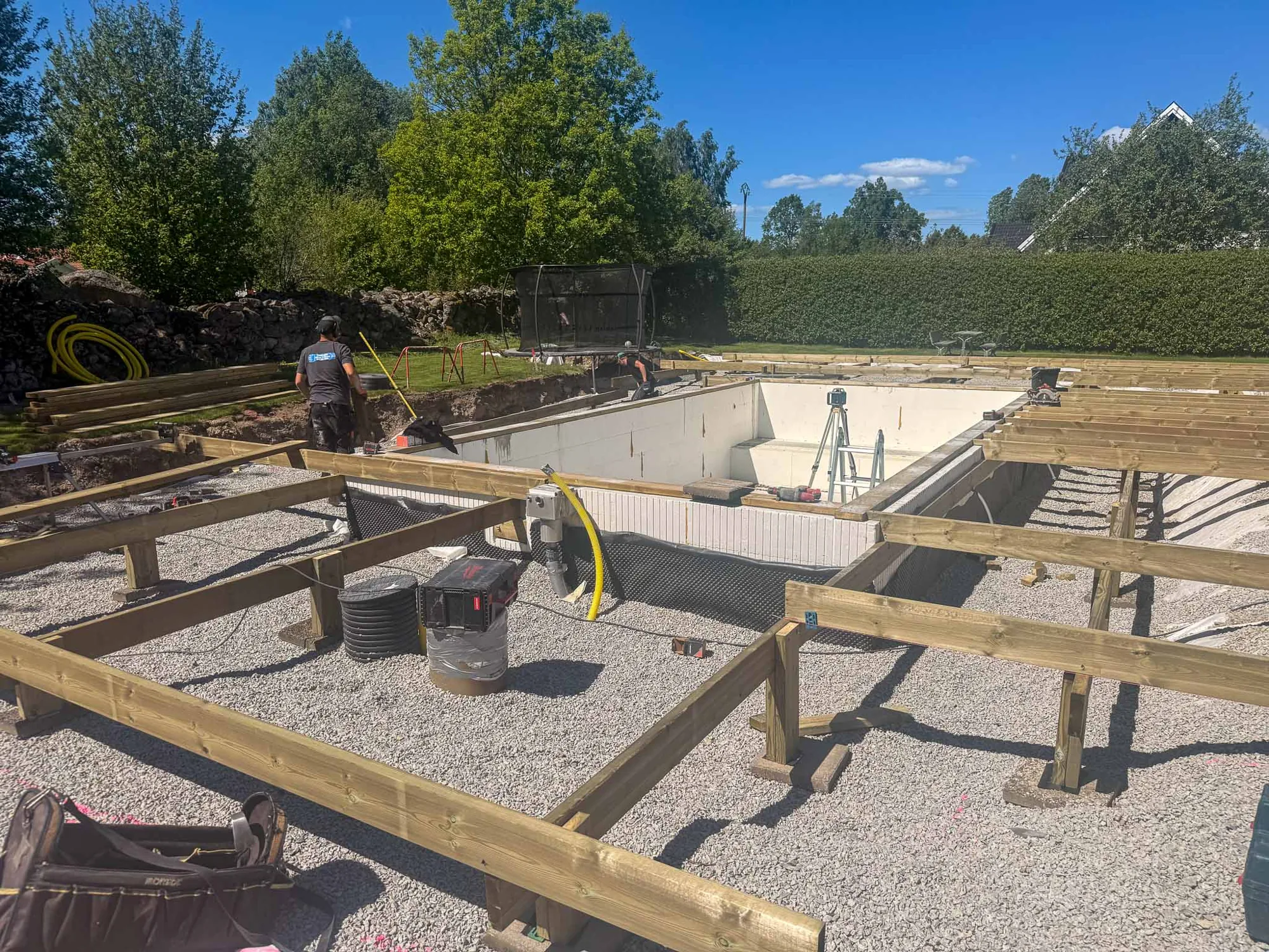 Pågående poolbygge med gjuten grund och regelverk i trä